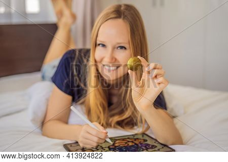 Nft Young Woman, A Digital Artist, Creates Digital Art On A Tablet At Home And Shows A Coin With The