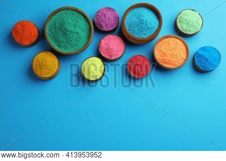Colorful Powders In Bowls On Light Blue Background, Flat Lay With Space For Text. Holi Festival Cele