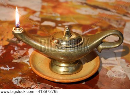 Ancient Oil Lamp With Burning Flame On A Marble Surface