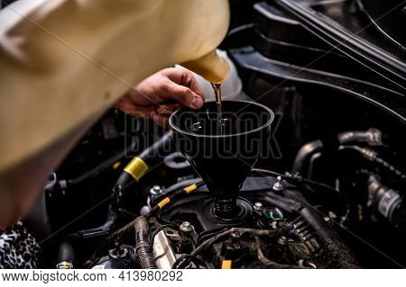 Close-up Of Mechanic Adding Oil With A Funnel