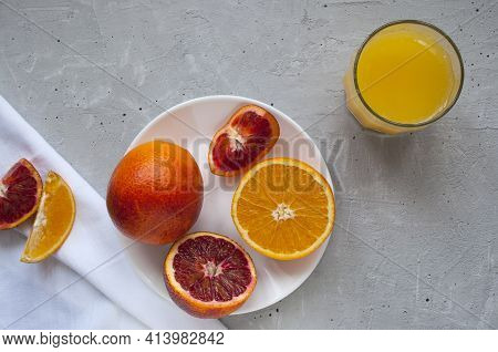Sweet And Juicy Blood Oranges And Oranges, Whole And Cut On A White Plate And Gkasses Of Fresh Orang