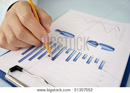 Man Holding A Pencil Working On A Graph