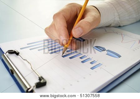Man Holding A Pencil Working On A Graph