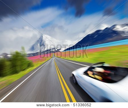 Mountain landscape with road and sports car in motion blur