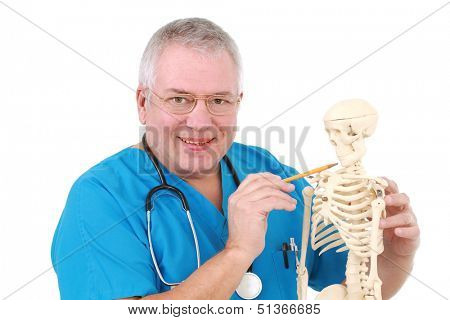 Man dressed in medical uniform inspects a replica of a human skeleton.
