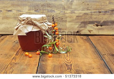 sea buckthorn berries juice on the glass jar on wooden background 
