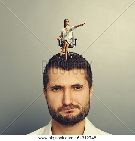earnest woman pointing at something and sitting on the head of displeased man