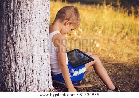 Boy Child Playing With Tablet Pc Outdoor With Summer Nature On Background Computer Game Dependence C