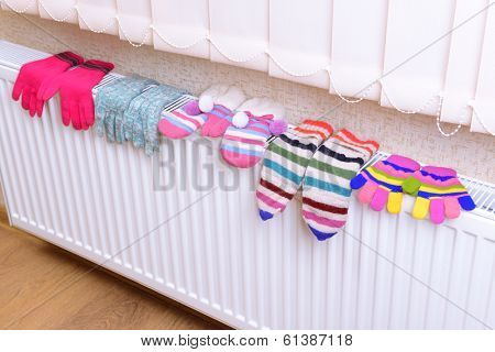 Knitted gloves drying on heating radiator