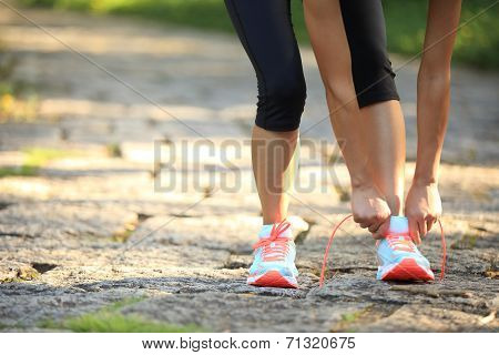 Young fitness woman tying shoelaces
