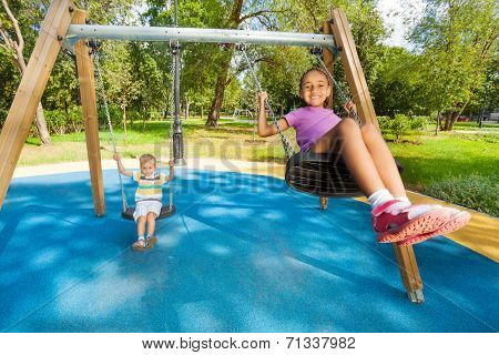 Boy and girl singing on swings