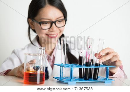 Asian lab people doing liquid sample analysis, on plain background.