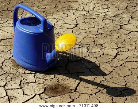 watering can full of water on dry cracked soil