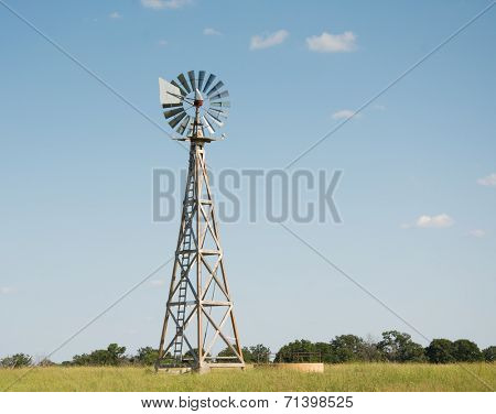 Windpump with a water tank at the base of it, with blades turning in the high winds
