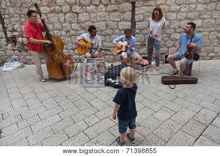 DUBROVNIK, CROATIA - MAY 26, 2014: Little boy watching band performing on Stradun.  Stradun is 300 meters long main pedestrian street in Dubrovnik.