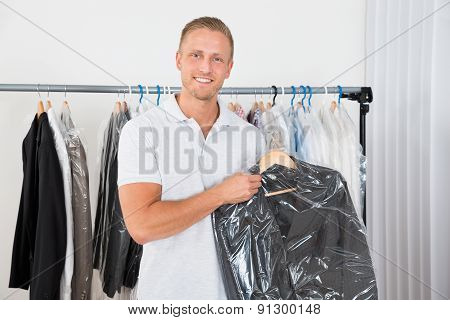 Man Holding Coat In Dry Cleaning Store