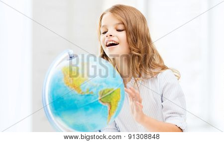 education and school concept - little student girl with globe at school