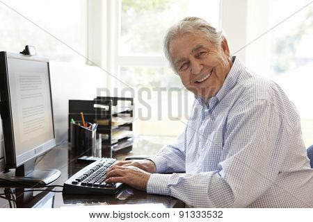 Senior Hispanic man working on computer at home