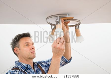 Technician Fixing Light On Ceiling