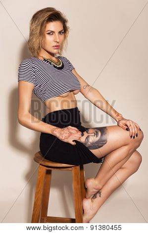 Beautiful sexy blonde woman with make up and mehendi tattoo in striples top and black skirt on neutr