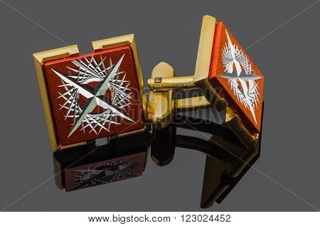 gold cufflinks on a dark reflective background