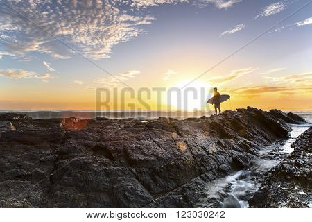 GOLD COAST, AUSTRALIA - JANUARY 2 2016: Silhouette of a surfer standing at the end of Currumbin Rock Gold Coast, at sunrise