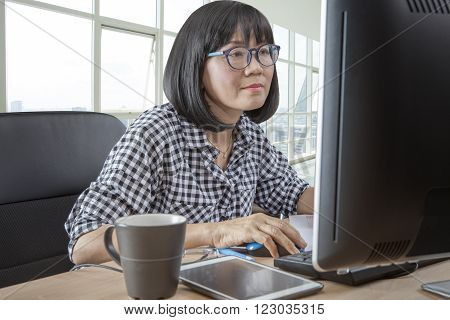 45s years woman working in front of computer monitor office life theme