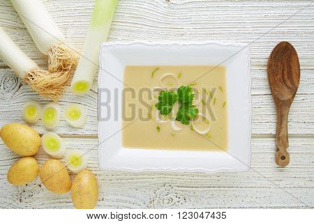 vichyssoise cream soup with leeks and potatoes on white wood table