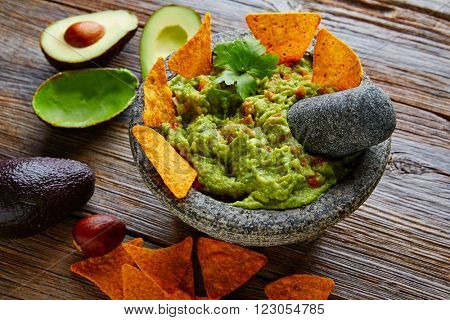 Guacamole with nachos avocado in Mexican molcajete in aged wood table