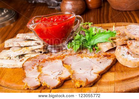 Meat platter with adjika sauce on wooden table