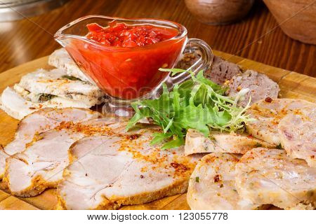 Meat platter with adjika sauce on wooden table