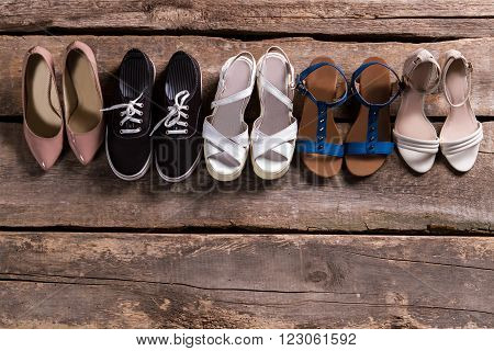 Pairs of woman's stylish footwear. Shoes on old wooden shelf. Shoe row at vintage store. Retro boutique footwear sale.