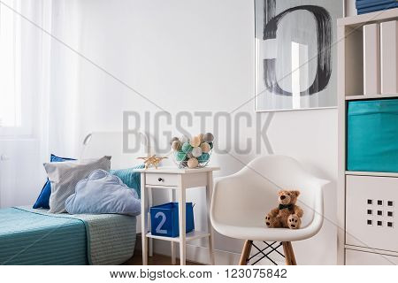 Seaside decorations on nightstand near blue single bed in modern children's room