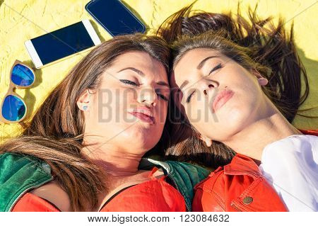 Young girls friends lying head to head top view - Beautiful women couple face from above are relaxing on the beach - Sleeping girlfriends enjoying sun in spring day - Concept of friendship and love