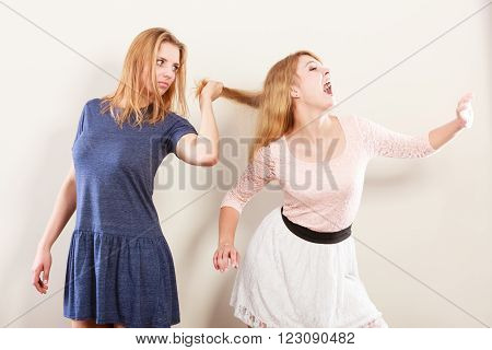 Aggressive mad women fighting each other pulling hair. Two young girls struggling win catfight. Violence.