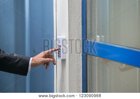 Close-up Of Mature Businessman Using Door Security System On Wall