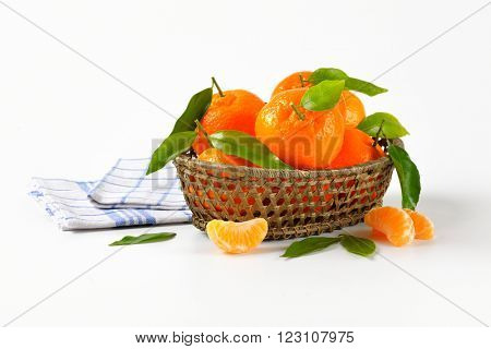 scuttle of ripe tangerines and checkered dishtowel on white background
