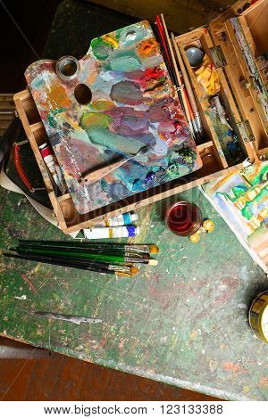 Workplace of the artist with brushes, oil paints, pallete, palette knife and tea