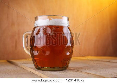 Dimpled mug with amber beer on a grunge wood surface