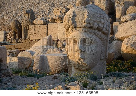 Goddess of Kommagene (Tyche) head - part od ancient sculpture on Mount Nemrut (Turkey). Scene in the sunset sun. Lion and Bird sculptures in background.