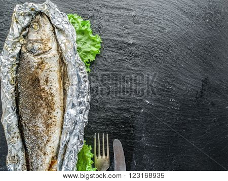 Grilled sea bass fish on the gray table.
