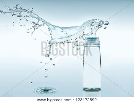 The  bottle of clear liquid stays on the turquoise water background with big  splash above the bottle