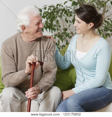 Old man holding a cane and smiling to his granddaughter