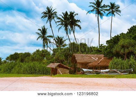 The hut of bamboo and fishing boats on the beautiful sandy beach on the island of Sri Lanka