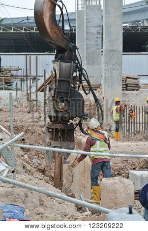 SELANGOR, MALAYSIA - MARCH 12, 2015: Sheet pile cofferdam driven machine at the construction site. This machine drove the sheet pile to the earth using vibrated hydraulic arm. Workers control.