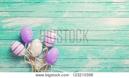 Easter/spring background. Decorative violet eggs on turquoise wooden background. Selective focus. Place for text. Toned image.