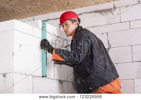 bricklayer puts a wall of aerated concrete blocks
