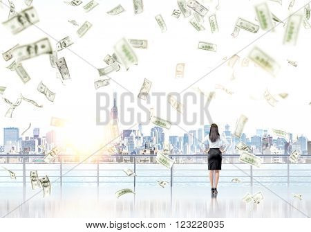 Businesswoman on enbankment looking at New York dollars falling from above. Back view. Concept of new start.