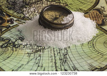 Metal antique compass on white ice floes on a world map background.
** Note: Shallow depth of field