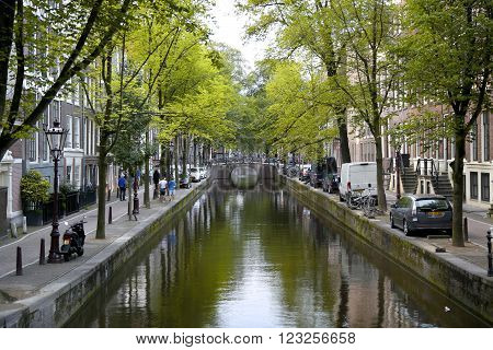 AMSTERDAM; THE NETHERLANDS - AUGUST 18; 2015: View on beautiful street Oudezijds Achterburgwal, street life, canal and tourists. Amsterdam is capital of the Netherlands on August 18; 2015.